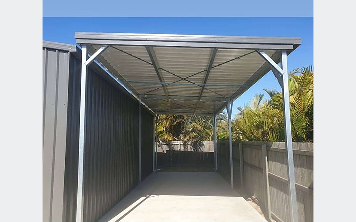 Open-sided caravan and boat cover with skillion roof attached to an existing shed, concrete floor and clear access underneath