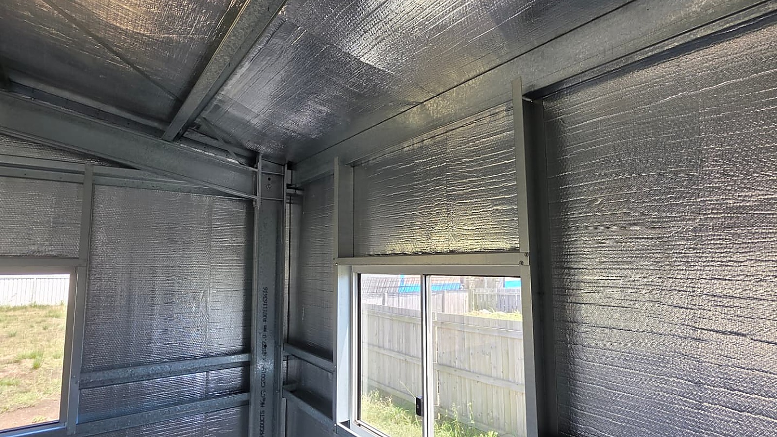 Shed interior lined with reflective foil-faced insulation blanket across the roof and walls, fitted by Spartan Sheds in Bundaberg QLD